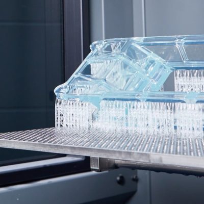 Clear plastic component being produced using an SLA (Stereolithography) 3D printer.